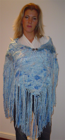 Poncho modelo cerrado de lana celeste tejido a mano, con flecos