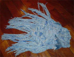 Poncho de lana celeste con apliques en piel y largos flecos